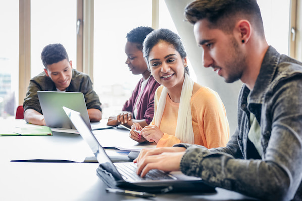 two people in an office using a laptop to find a wordpress theme for adsense for their website